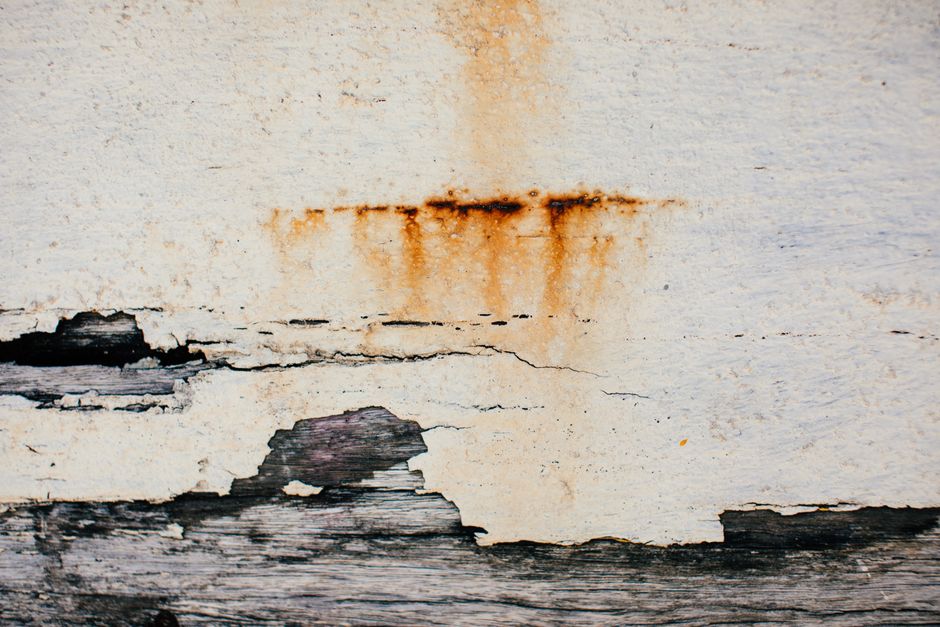 Mur présentant des coulures et traces d'infiltration d'eau sous un enduit dégradé