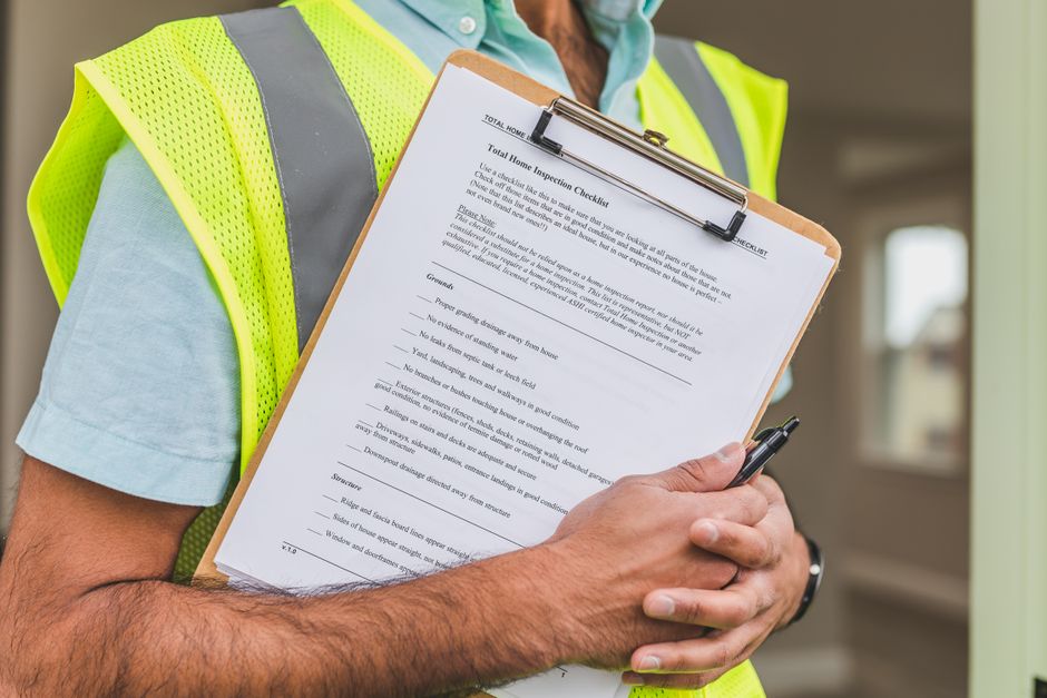 Expert en gilet de sécurité remplissant une fiche de constat de sinistre dans une habitation